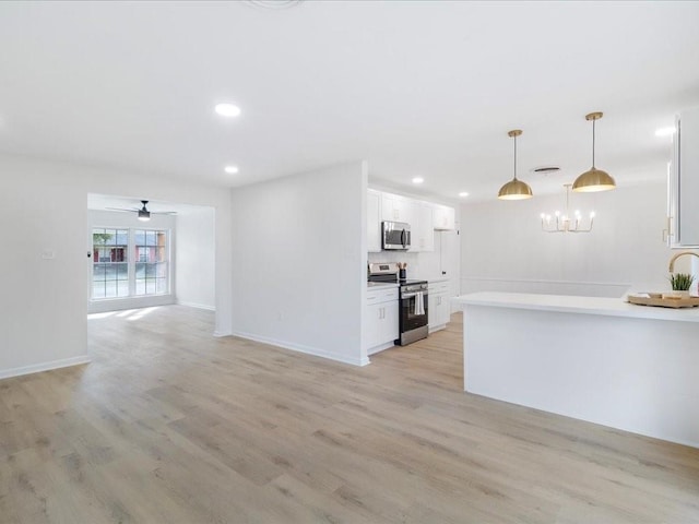 kitchen featuring white cabinetry, appliances with stainless steel finishes, light hardwood / wood-style floors, and decorative light fixtures