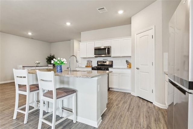 kitchen featuring an island with sink, appliances with stainless steel finishes, sink, and white cabinets