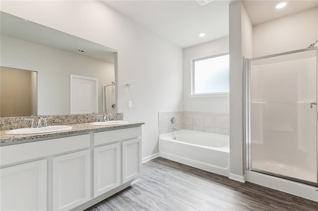 bathroom with wood-type flooring, shower with separate bathtub, and vanity