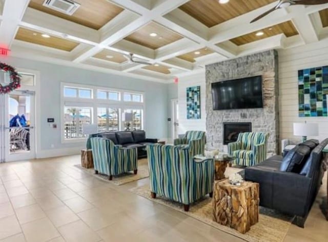 living room featuring coffered ceiling, a stone fireplace, wooden ceiling, ceiling fan, and beam ceiling