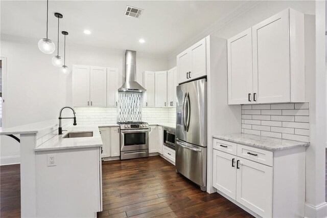 kitchen with sink, white cabinetry, stainless steel appliances, kitchen peninsula, and wall chimney exhaust hood