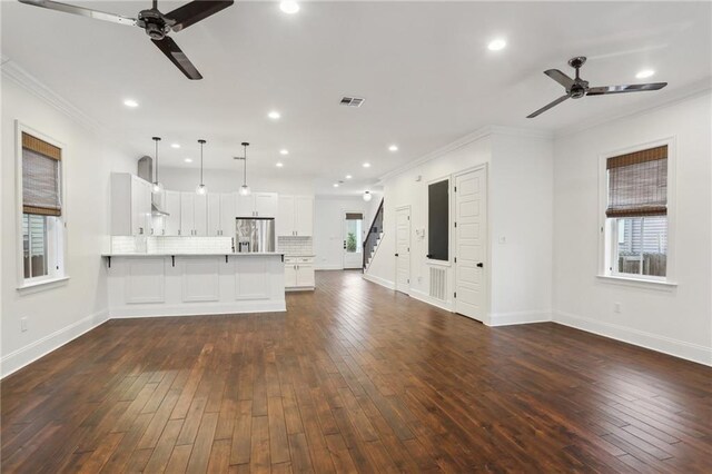 unfurnished living room featuring ceiling fan, ornamental molding, and dark hardwood / wood-style floors