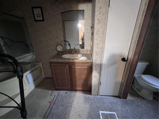 bathroom featuring tile patterned floors, vanity, toilet, and a washtub