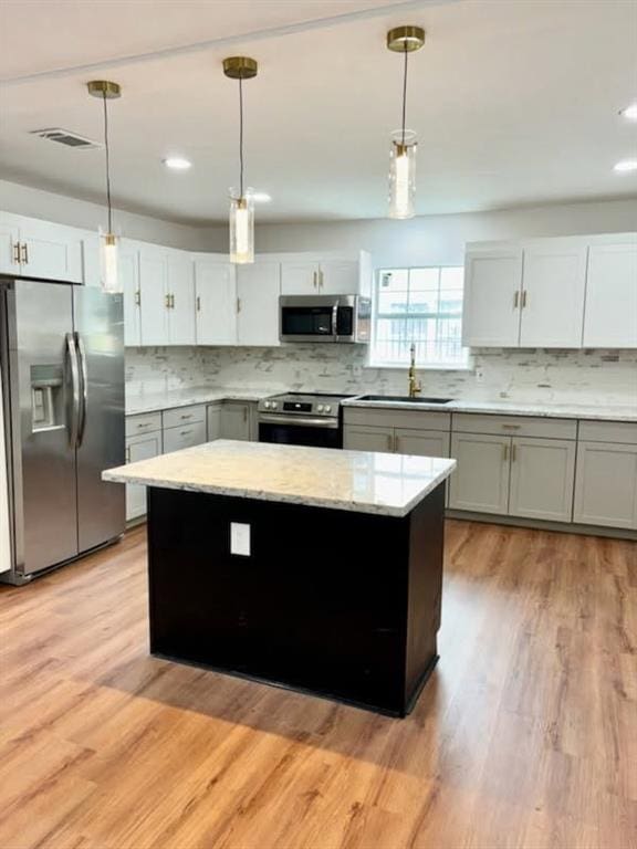 kitchen with stainless steel appliances, a kitchen island, sink, and pendant lighting