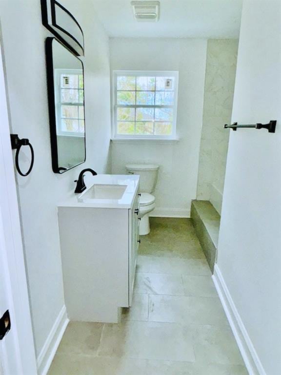 bathroom featuring vanity, plenty of natural light, a shower, and toilet