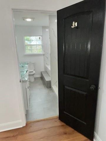 bathroom with hardwood / wood-style flooring, toilet, and a shower