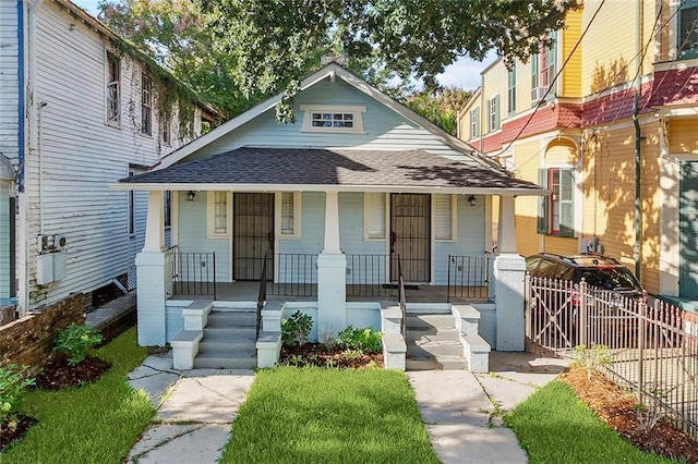 view of front of house featuring covered porch, roof with shingles, fence, and a gate