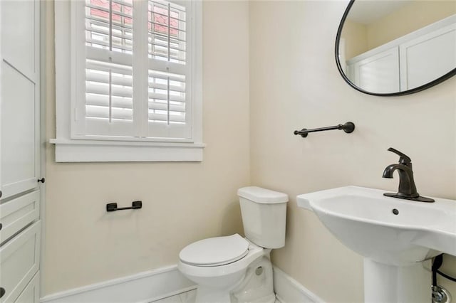 bathroom with a sink, toilet, and baseboards