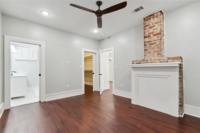 unfurnished bedroom with a walk in closet, recessed lighting, visible vents, wood finished floors, and baseboards