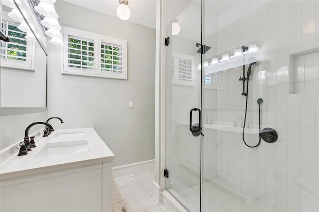 full bath featuring a sink, baseboards, marble finish floor, double vanity, and a stall shower