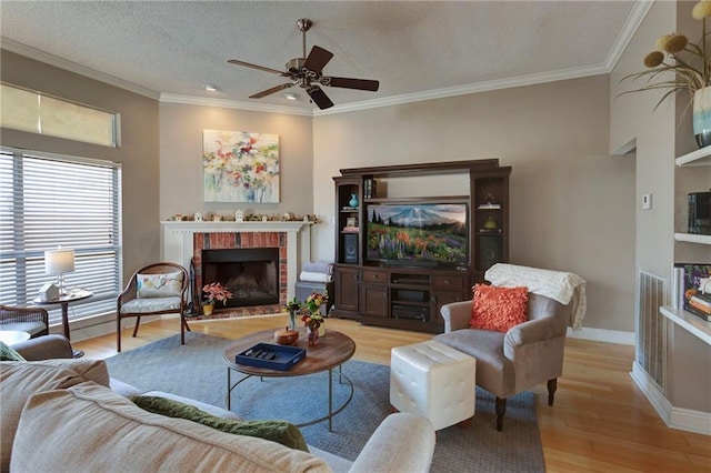 living room featuring light hardwood / wood-style flooring, crown molding, a fireplace, and ceiling fan