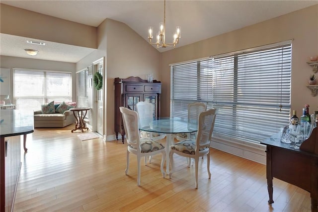 dining space with lofted ceiling, light hardwood / wood-style flooring, and a notable chandelier