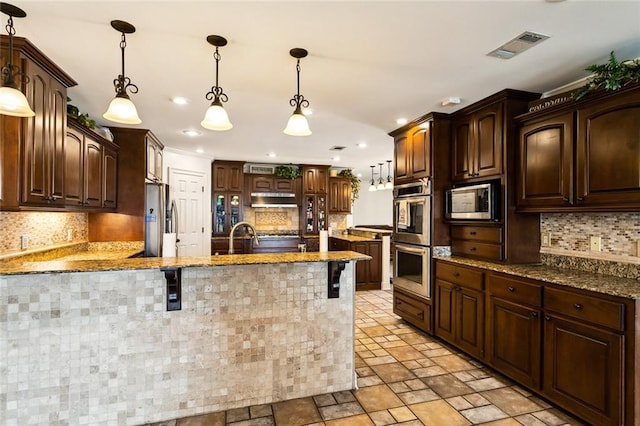 kitchen with pendant lighting, dark brown cabinetry, stainless steel appliances, and tasteful backsplash