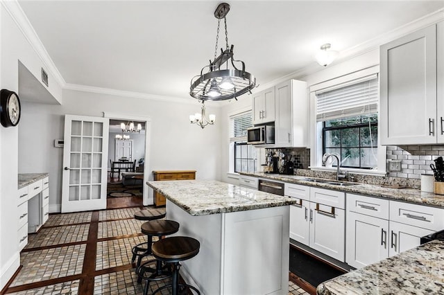 kitchen with appliances with stainless steel finishes, white cabinetry, hanging light fixtures, a center island, and a kitchen bar