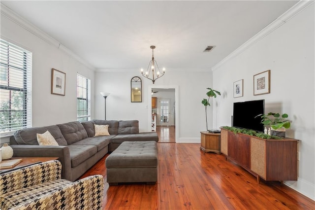 living room with crown molding, dark wood-type flooring, and a chandelier