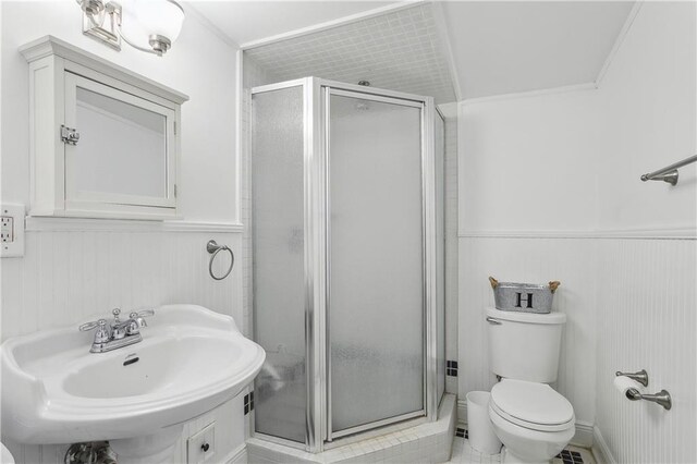 bathroom featuring sink, a shower with door, and toilet