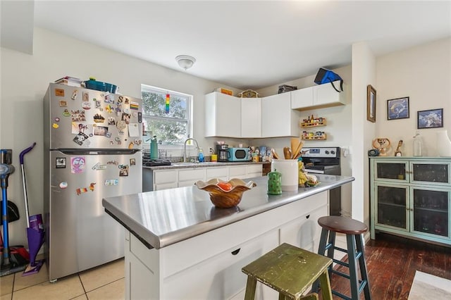 kitchen with white cabinetry, stainless steel fridge, sink, and a kitchen island