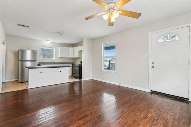 interior space featuring stainless steel fridge, electric range oven, a center island, light hardwood / wood-style floors, and white cabinets