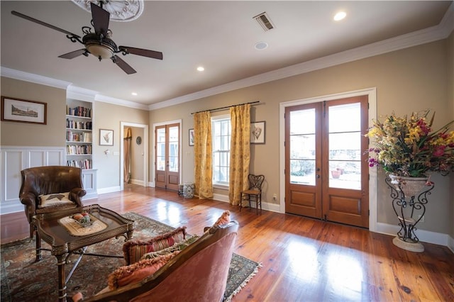 living room with crown molding, light hardwood / wood-style flooring, a wealth of natural light, and french doors