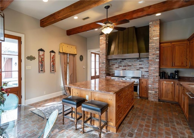 kitchen featuring a breakfast bar area, light stone counters, high end stainless steel range, custom range hood, and a kitchen island