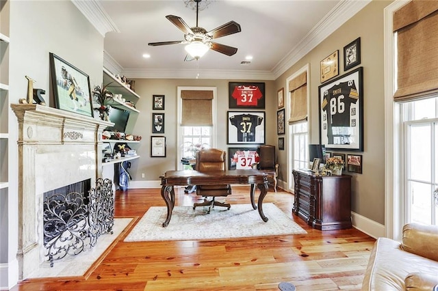 office with crown molding, a fireplace, ceiling fan, and light wood-type flooring