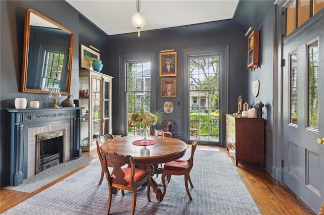 dining area with a wealth of natural light, hardwood / wood-style floors, and a high end fireplace