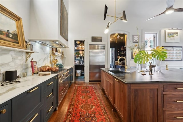 kitchen featuring sink, dark wood-type flooring, backsplash, high end appliances, and extractor fan