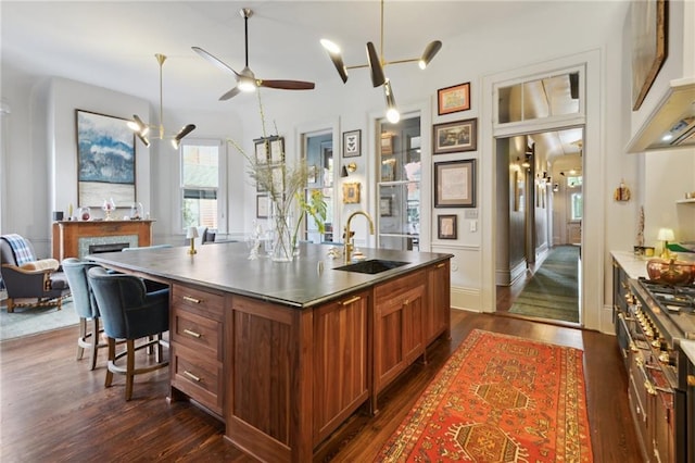 kitchen featuring dark wood-type flooring, sink, a breakfast bar area, a center island with sink, and range with two ovens