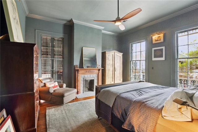 bedroom featuring ornamental molding, dark wood-type flooring, ceiling fan, and a high end fireplace