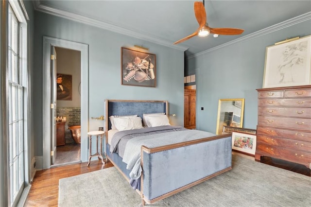 bedroom featuring crown molding, light hardwood / wood-style flooring, ensuite bath, and ceiling fan