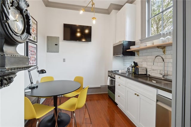 kitchen featuring stainless steel stove, white cabinetry, sink, ornamental molding, and electric panel