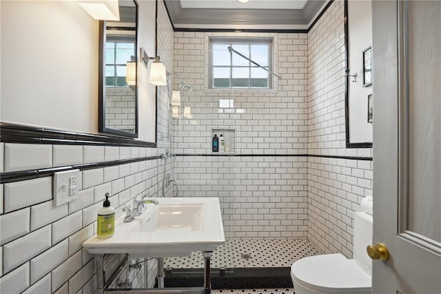 bathroom with sink, tile walls, tiled shower, toilet, and crown molding