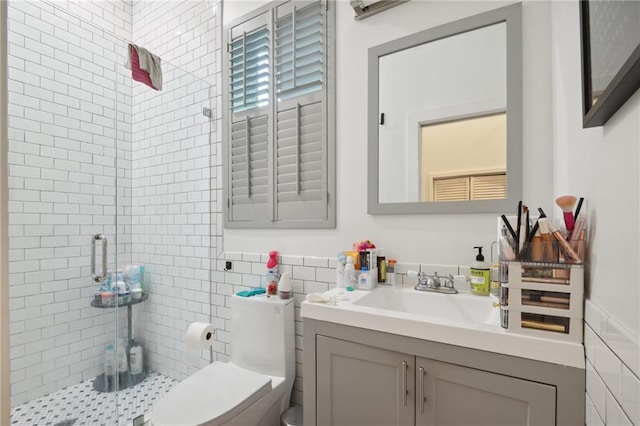 bathroom with vanity, toilet, a shower with shower door, and tile walls