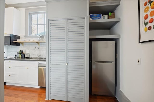 1013 Race St, New Orleans, LA 70130 - kitchen with sink, white cabinetry, light wood-type flooring, stainless steel appliances, and backsplash