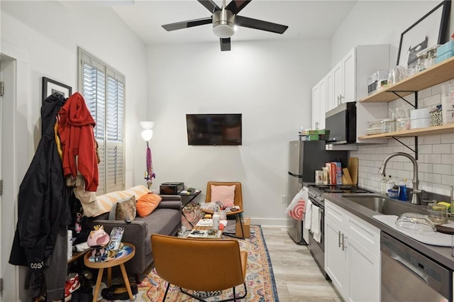 1013 Race St, New Orleans, LA 70130 - kitchen featuring tasteful backsplash, white cabinetry, sink, light hardwood / wood-style floors, and stainless steel appliances