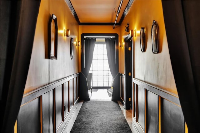 hallway featuring ornamental molding and dark carpet