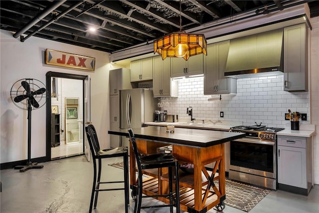 kitchen with sink, decorative backsplash, stainless steel range with gas stovetop, green cabinets, and wall chimney range hood