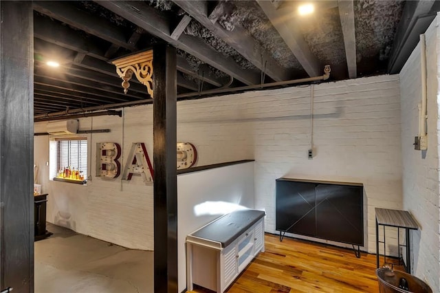 basement with a wall mounted air conditioner and light wood-type flooring