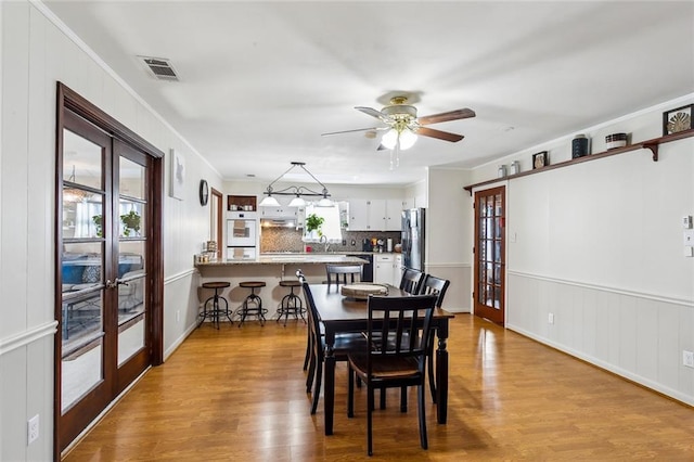 dining area with french doors, ceiling fan, and light wood-type flooring