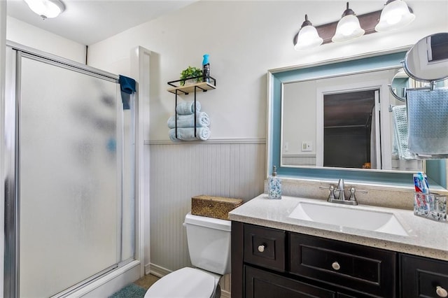 bathroom featuring vanity, toilet, and a shower with door