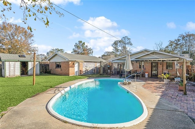 view of pool featuring a storage unit, a patio, and a lawn