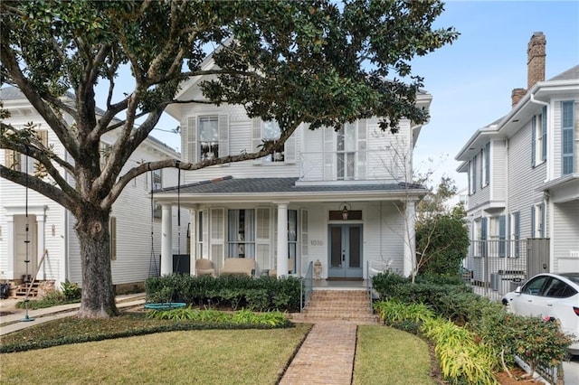 view of front of home with french doors, covered porch, and a front yard