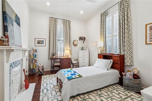 bedroom with a premium fireplace, ornamental molding, and dark hardwood / wood-style floors