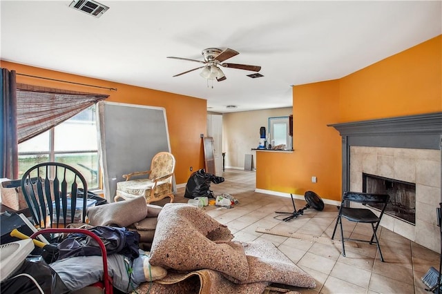 living room featuring a tile fireplace and ceiling fan