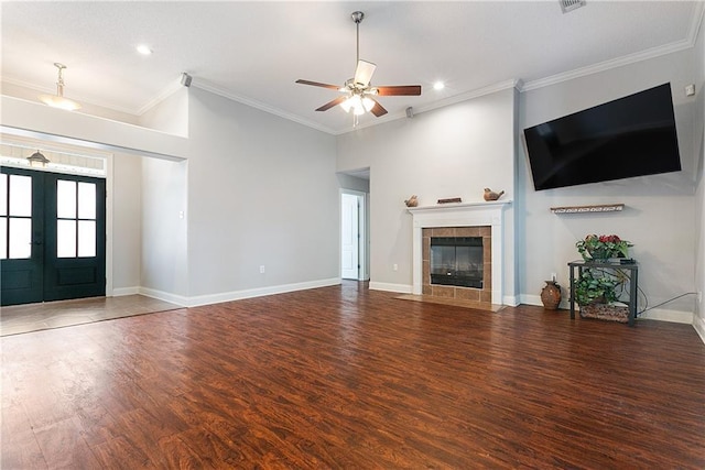 unfurnished living room featuring dark wood-type flooring, a tile fireplace, ceiling fan, ornamental molding, and french doors