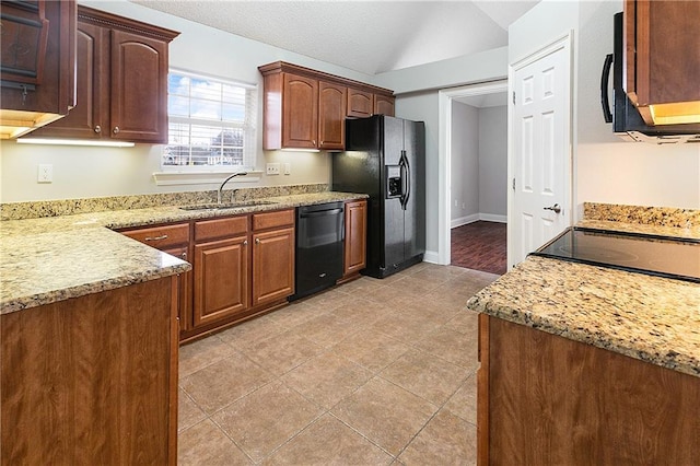 kitchen featuring light stone counters, sink, black appliances, and lofted ceiling