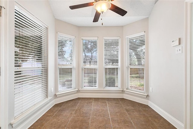 unfurnished dining area with dark tile patterned floors, a textured ceiling, and ceiling fan