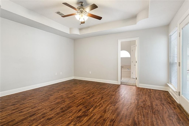 unfurnished bedroom featuring ceiling fan, dark hardwood / wood-style flooring, a raised ceiling, and ensuite bath