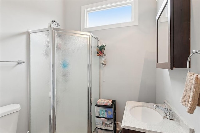 bathroom with vanity, a shower with shower door, and toilet