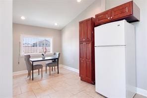 kitchen featuring vaulted ceiling and white fridge